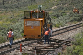 After the ties were removed, a pair of maintenance of way (MOW) workers salvage the old tie plates (the metal rectangular pieces that sit between the ties and the rails).  They use long rods to pick the tie plates up.  (It sure beats bending over for each one!)  CRW 2601a